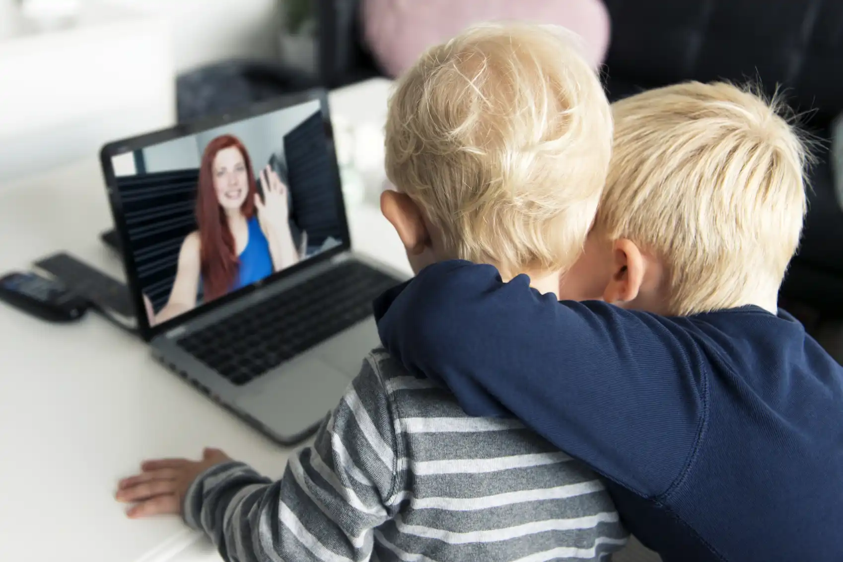 two children looking at a person on a laptop screen.